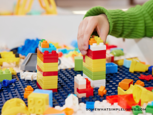 child's hands playing with Legos on a white table