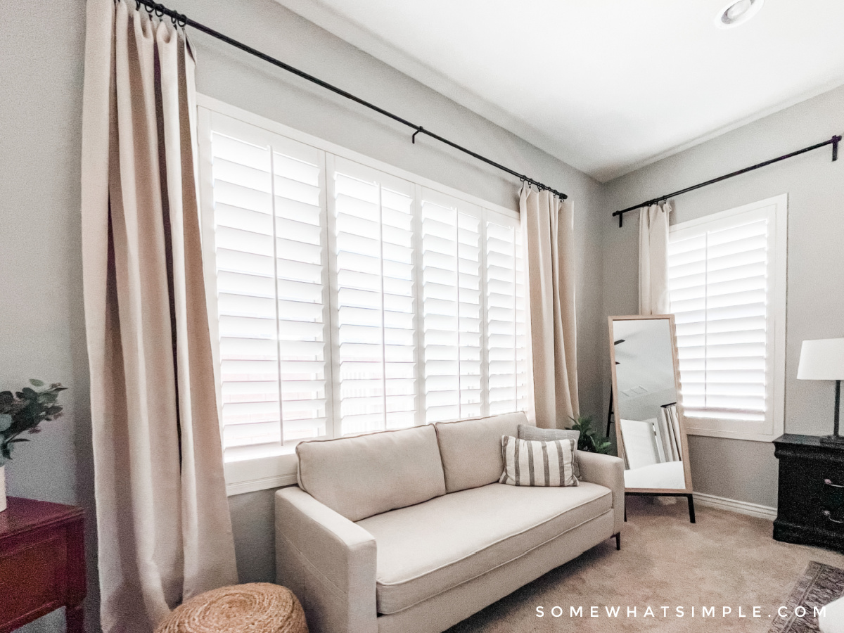 beige couch in a master bedroom under a big window