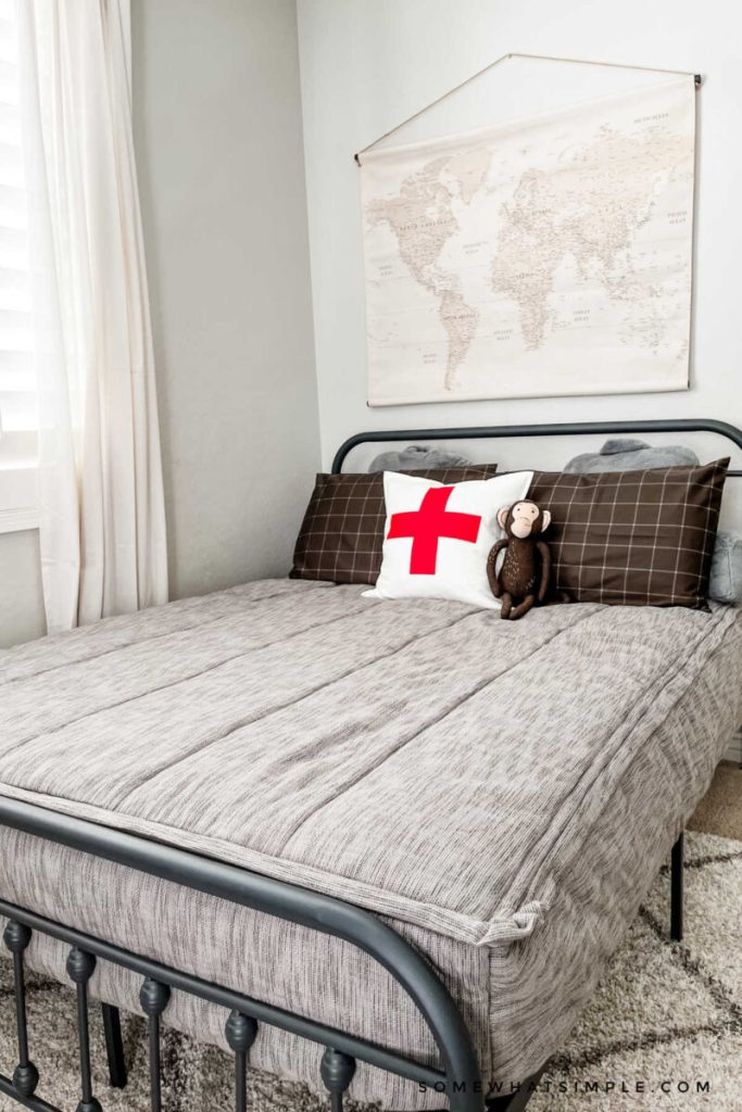 long image of a boys bed with a swiss cross pillow on it