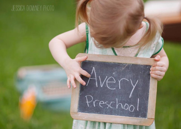 a little girl holding a chalkboard that says Avery preschool