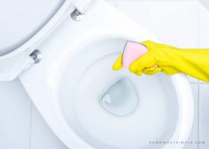 yellow gloves scrubbing toilet