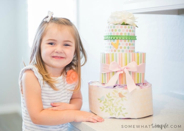 cute little girl next to a diaper cake that will be given as a baby shower gift