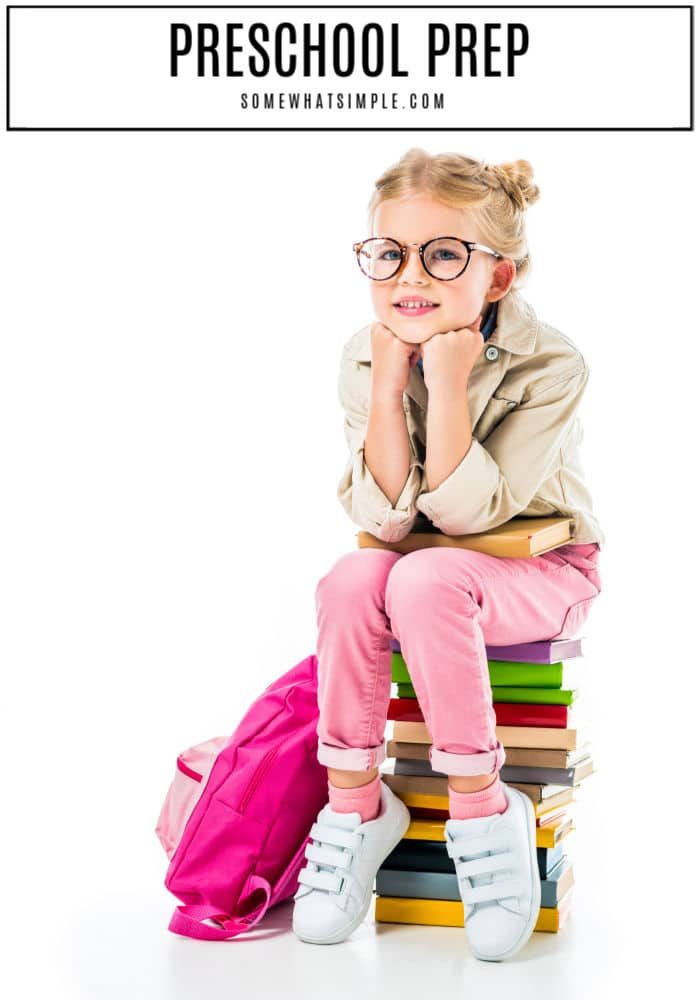 little girl sitting on a stack of books with backpack preparing for preschool