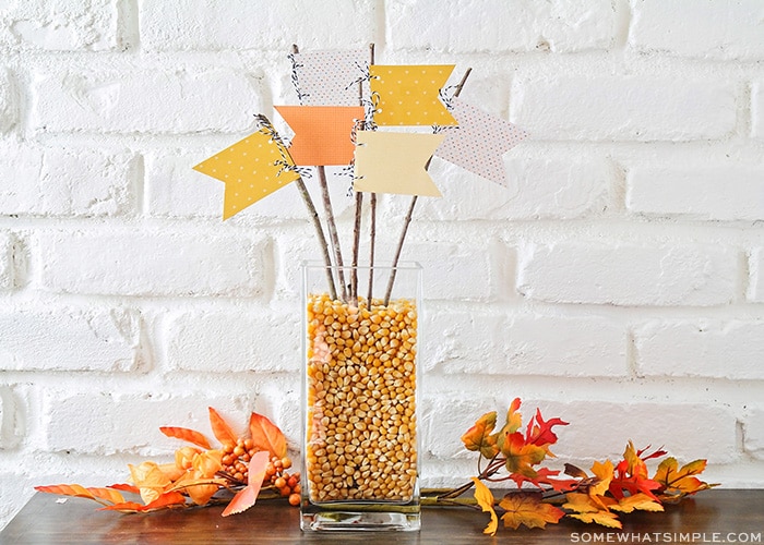 a fall centerpiece made with pennants and twigs on a table