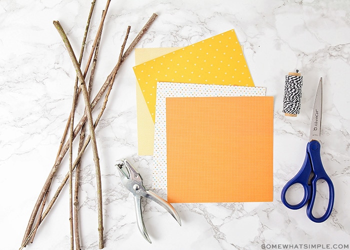 twigs, fall colored card stock and other supplies on a table