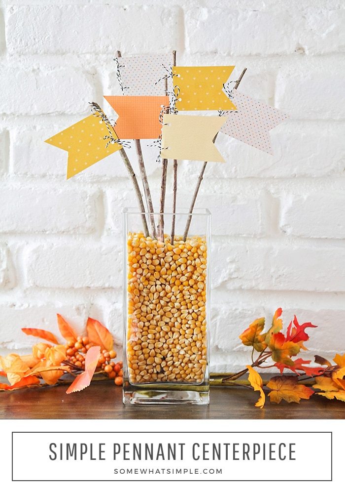 a fall table centerpiece made with a vase full of popcorn kernels and pennants stuck inside.