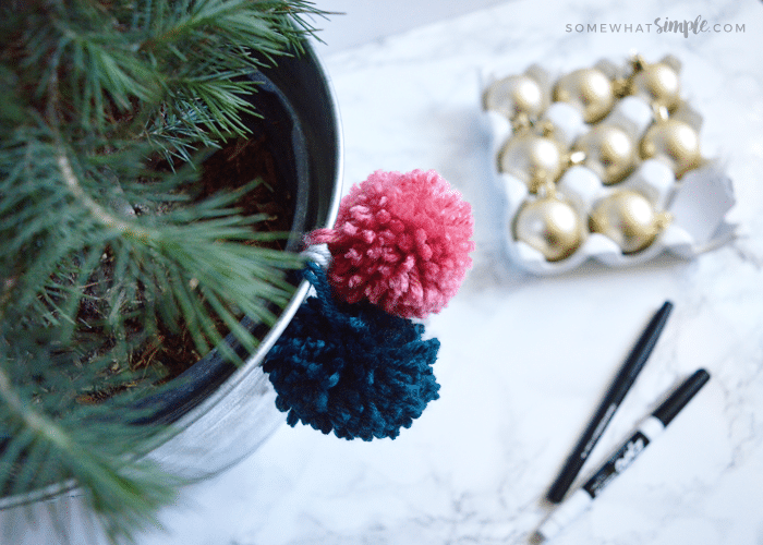 pink and blue pom poms hanging from a christmas tree