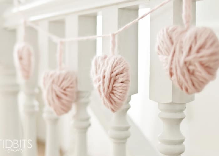 hearts made out of yarn hanging on a banister. diy valentine decor