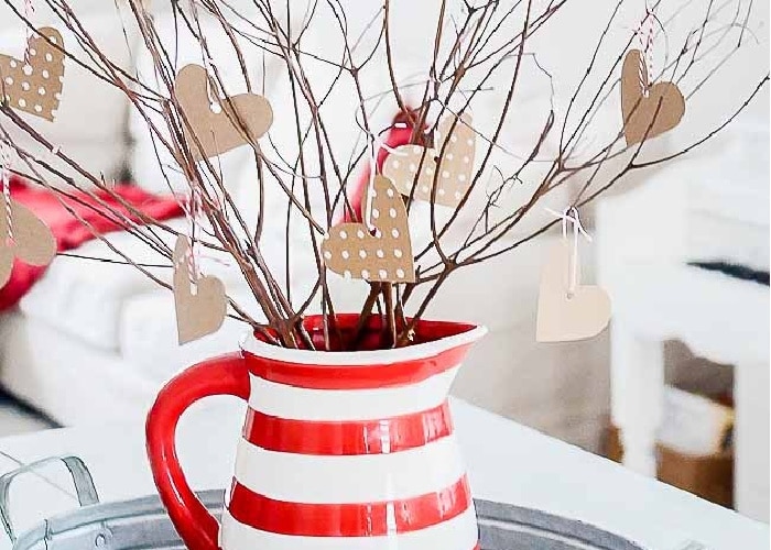 branches from a tree in a red and white vase with paper hearts stuck to the branches