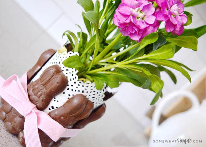 chocolate bunnys tied around a vase of flowers with a pink ribbon