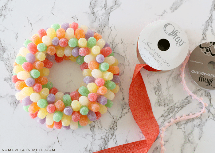 spool of orange ribbon laying next to a gumdrop wreath