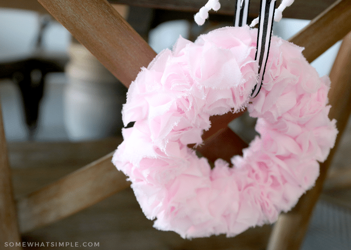 pink wreath hanging on the back of a chair