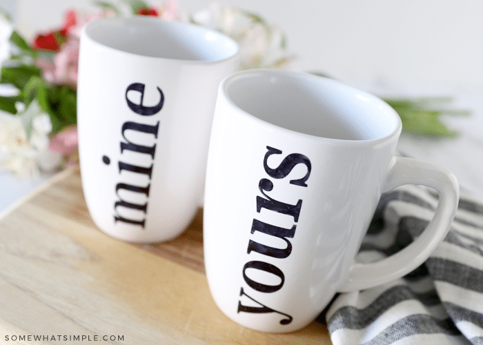 close up of 2 white mugs that say "mine" and "yours" on the counter