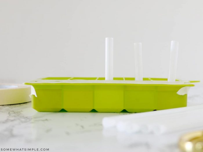 pouring chalking into an ice cube tray and sticking straws in each compartment