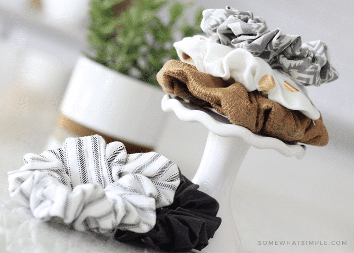 the DIY hair scrunchies stacked on top of each other on a small stand with two more scrunchies lying next to the stand on a counter