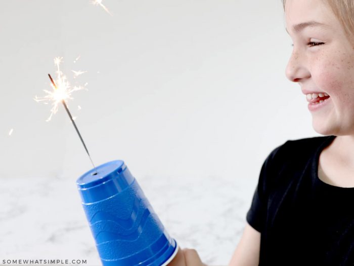 little girl holding a sparkler safety cup