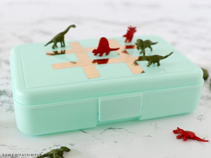 dinosaur tic tac toe markers on top of a plastic pencil box