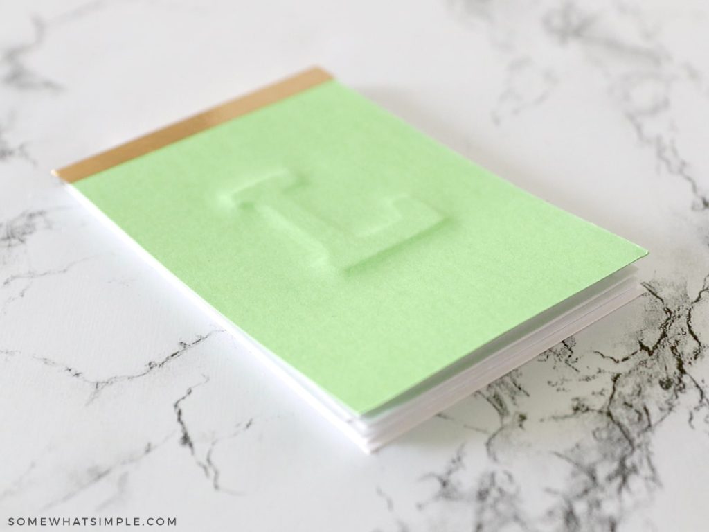 green notepad with a letter L on the front