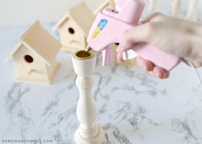adding some hot glue to the rim of a wood candlestick