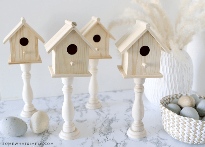 4 wood birdhouses with a basket of eggs on the side