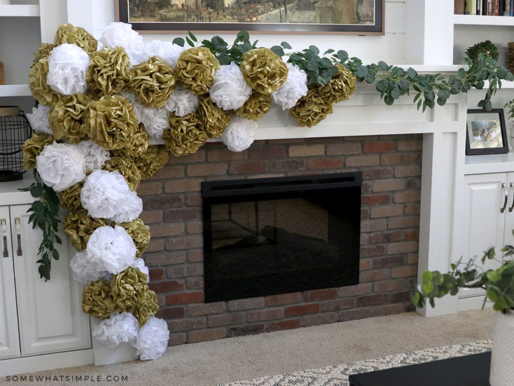 a christmas mantle with greenerey and tissue paper pom poms