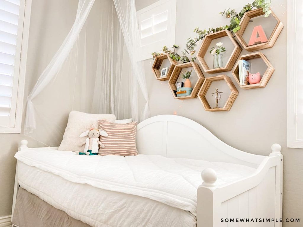 a girl's white day bed with mosquito net and wall decor behind the bed