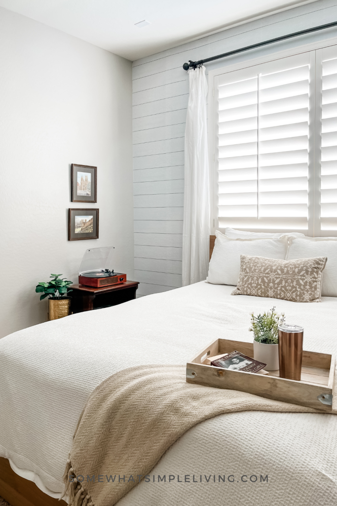 long image of a close up of a bed with a draped blanket over the corner and a breakfast tray