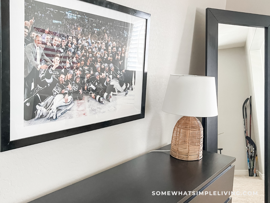 teen boy's bedroom dresser with brown lamp and hockey picture hanging on the wall