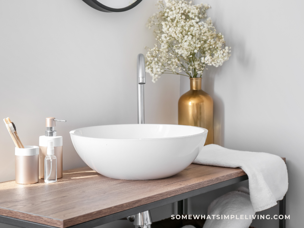 Close up of a clean bathroom sink with flowers and a hand tawel