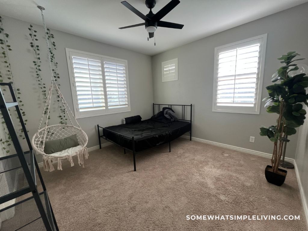 before picture of a guest room with a black bed and random items strewn about