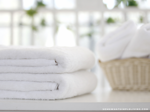 2 white towels next to a basket of clean laundry