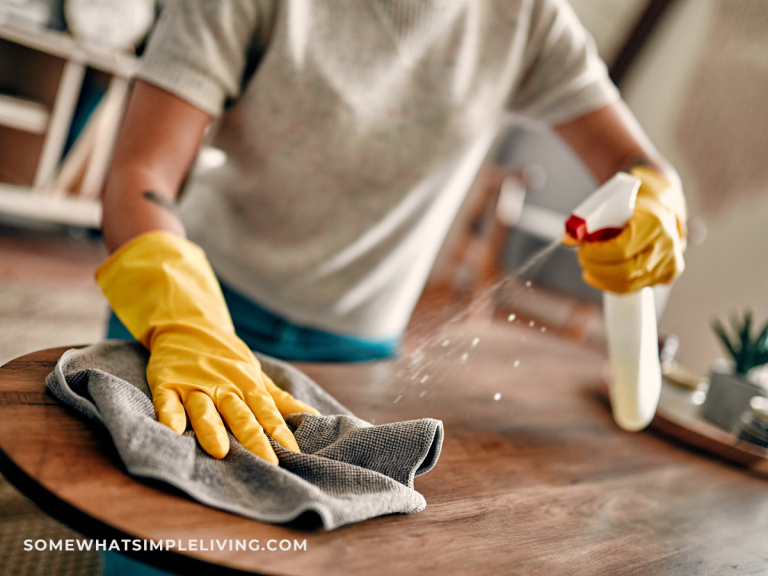 woman spraying and wiping a wood table