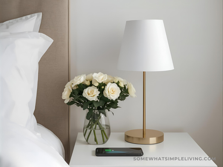 white nightstand with gold lamp, fresh flowers, and a cell phone charging