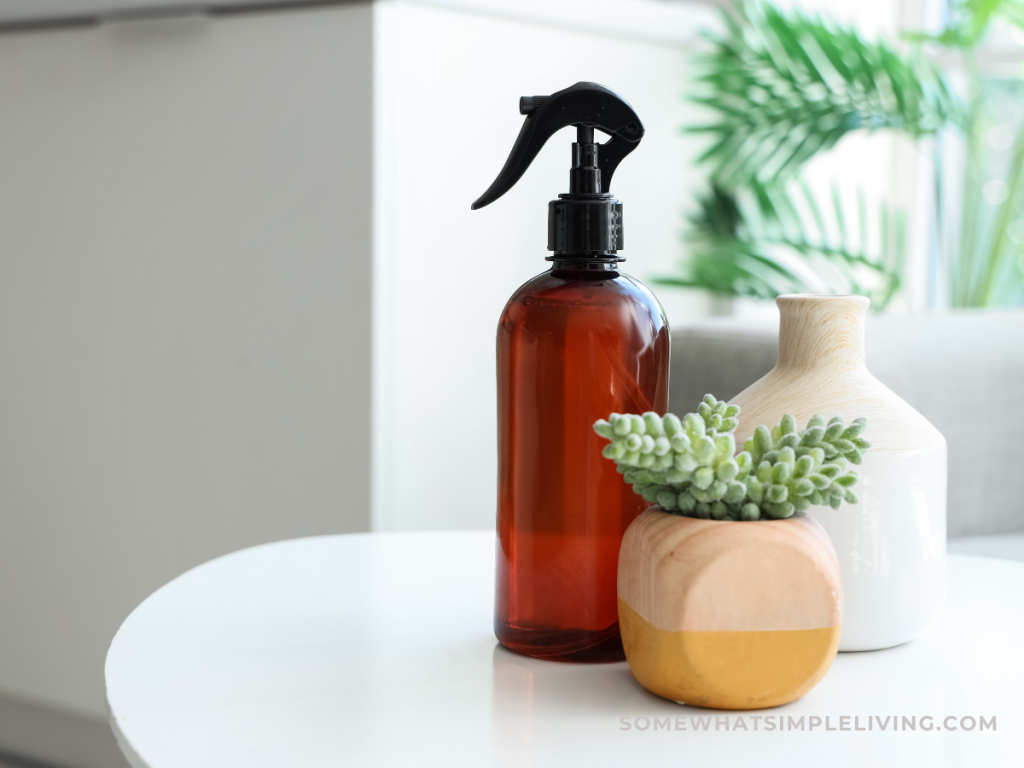 bottle of air freshener on a white table next to a small plant
